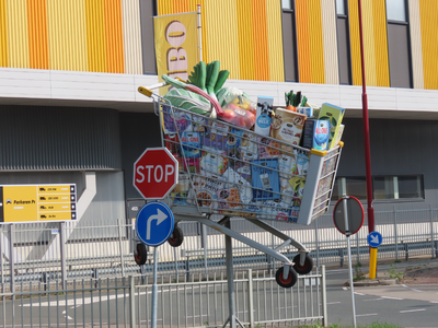 912628 Afbeelding van een vergrote winkelwagen vol boodschappen als reclame-uiting bij de ingang van het in 2020 ...